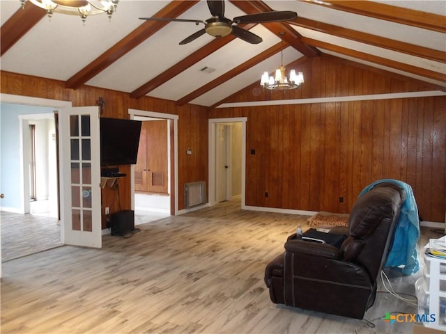 living area featuring vaulted ceiling with beams, ceiling fan with notable chandelier, wood walls, french doors, and light wood-type flooring