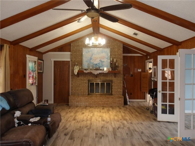 living room with lofted ceiling with beams, wood walls, a brick fireplace, and wood finished floors