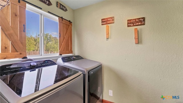 laundry area featuring washer and dryer, a barn door, and a textured wall