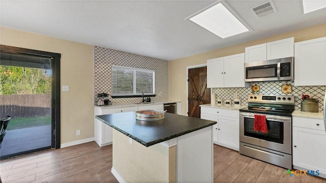 kitchen featuring stainless steel appliances, light wood finished floors, white cabinets, and backsplash
