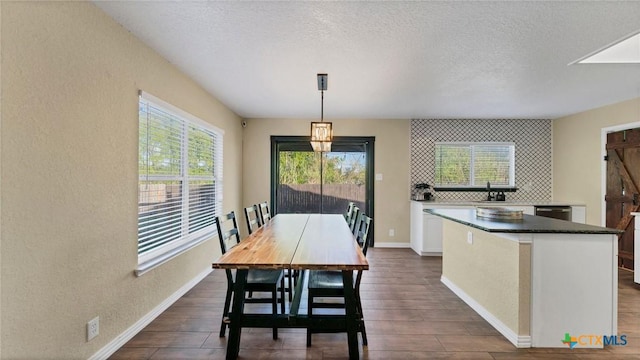 dining area featuring dark wood finished floors, a textured wall, a textured ceiling, and baseboards