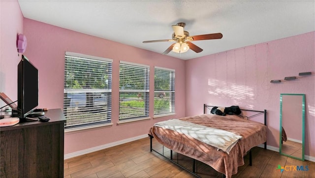 bedroom featuring wood finished floors, baseboards, and a ceiling fan
