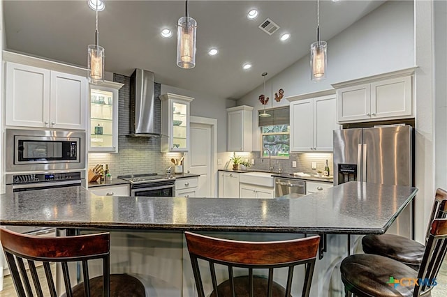 1002 Merry Ln, Kingsland, TX 78639 - kitchen with wall chimney exhaust hood, appliances with stainless steel finishes, vaulted ceiling, backsplash, and a kitchen bar