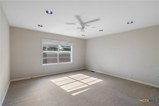 carpeted empty room with ceiling fan and crown molding