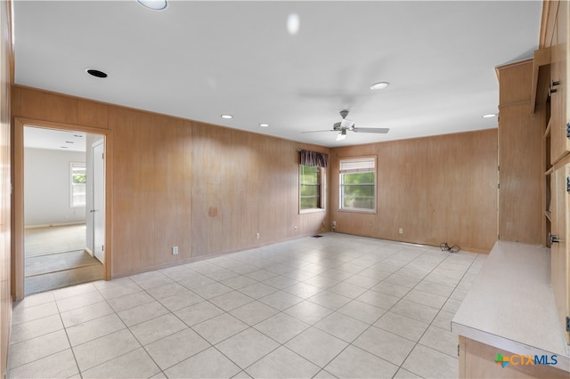 tiled spare room featuring wooden walls and ceiling fan