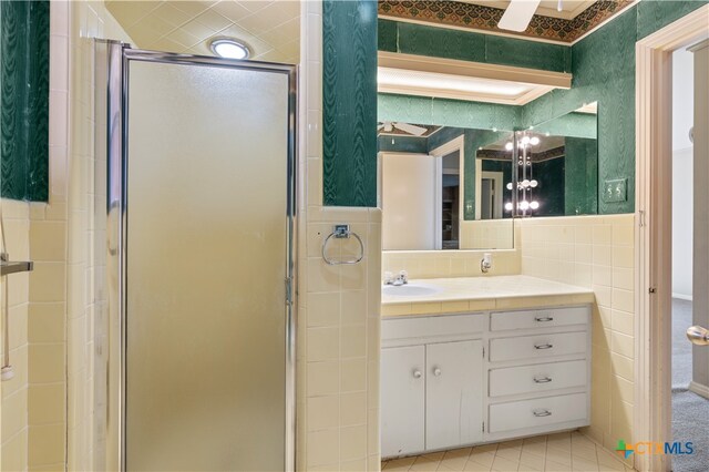 bathroom with walk in shower, vanity, and tile walls