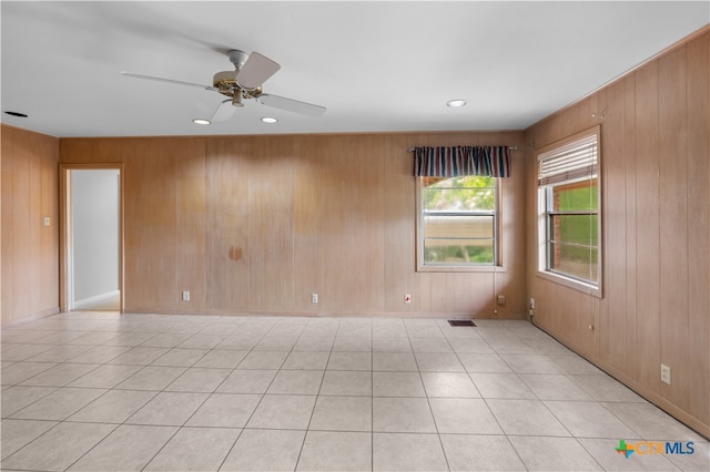 spare room featuring wooden walls, ceiling fan, and light tile patterned floors