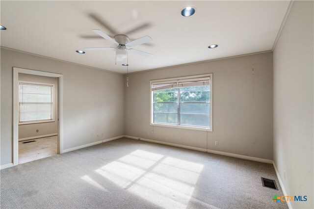 carpeted empty room with ornamental molding, ceiling fan, and plenty of natural light