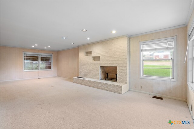 unfurnished living room featuring light colored carpet, ornamental molding, and a fireplace