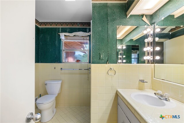 bathroom with tile patterned flooring, vanity, toilet, and tile walls