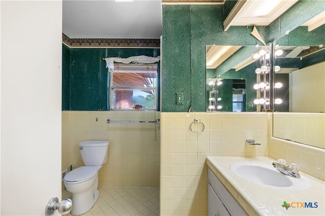701 Live Oak St, Gatesville, TX 76528 - bathroom featuring tile walls, toilet, vanity, ornamental molding, and tile patterned flooring