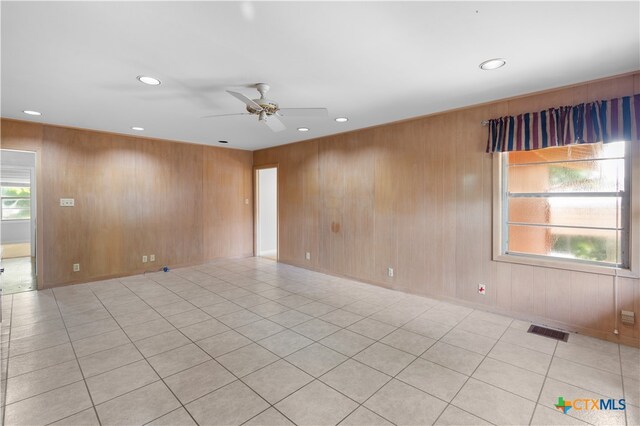 tiled empty room with wood walls and ceiling fan