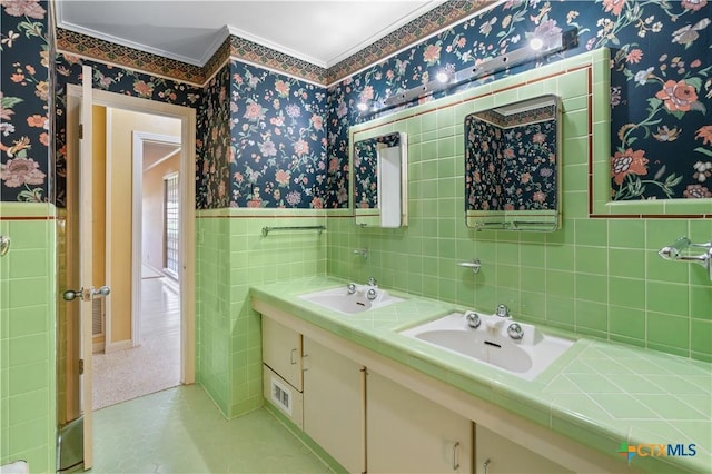 701 Live Oak St, Gatesville, TX 76528 - full bathroom featuring ornamental molding, wallpapered walls, double vanity, a wainscoted wall, and tile walls
