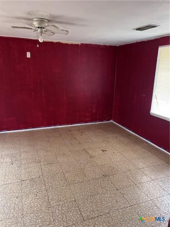 728 W Franklin St, Goliad, TX 77963 - empty room featuring a ceiling fan, wooden walls, and tile patterned floors