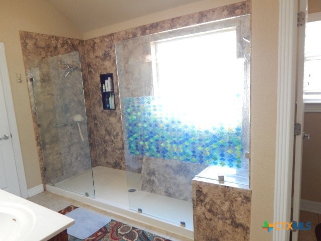 bathroom with a wealth of natural light, tiled shower, and lofted ceiling