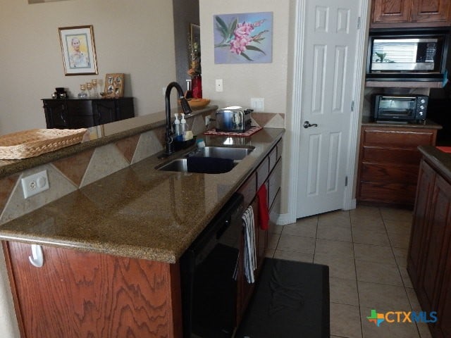 kitchen with light tile patterned flooring, black dishwasher, stone countertops, sink, and stainless steel microwave