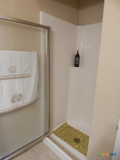 bathroom with walk in shower and tile patterned flooring