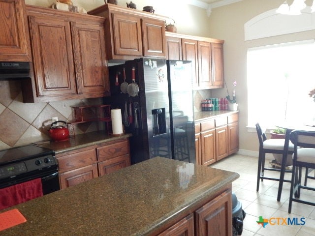 kitchen featuring black appliances, tasteful backsplash, crown molding, range hood, and light tile patterned floors