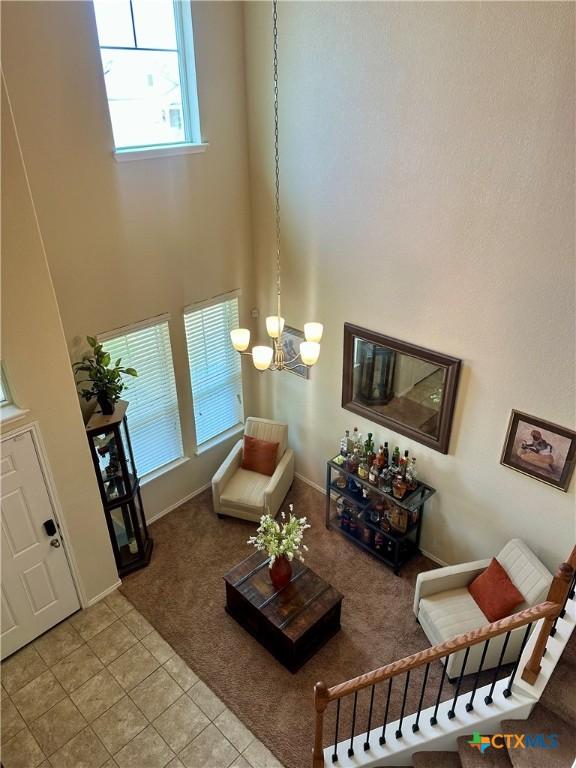 9516 Glynhill Ct, Killeen, TX 76542 - carpeted living area featuring tile patterned flooring, an inviting chandelier, a towering ceiling, and a healthy amount of sunlight