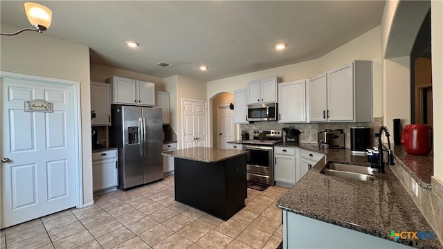 9516 Glynhill Ct, Killeen, TX 76542 - kitchen featuring arched walkways, a kitchen island, a sink, stainless steel appliances, and backsplash