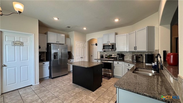 9516 Glynhill Ct, Killeen, TX 76542 - kitchen featuring tasteful backsplash, arched walkways, a center island, appliances with stainless steel finishes, and a sink