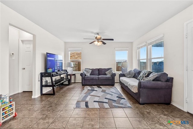 living room featuring baseboards, light tile patterned floors, and ceiling fan