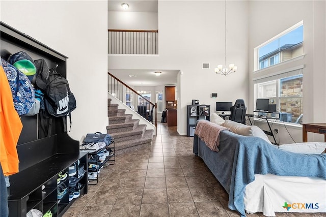 living room featuring a high ceiling, an inviting chandelier, stairway, and visible vents