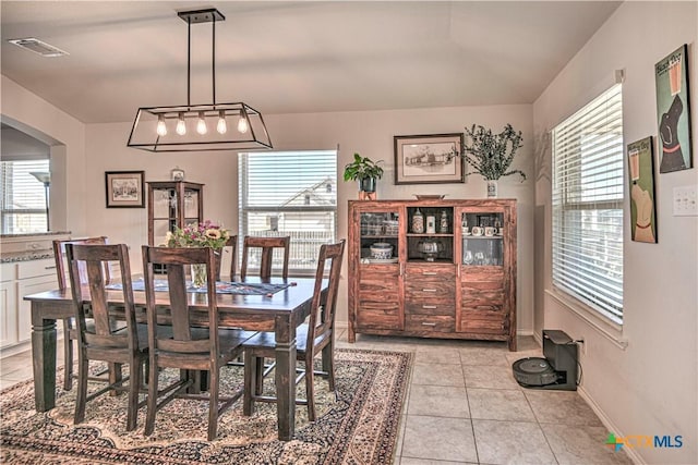 dining space featuring arched walkways, light tile patterned floors, a healthy amount of sunlight, and visible vents