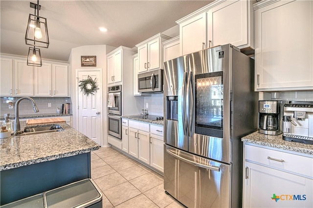 kitchen with a sink, white cabinetry, appliances with stainless steel finishes, light tile patterned flooring, and decorative backsplash