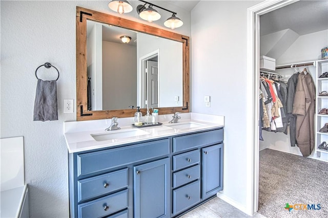 full bathroom featuring a walk in closet, double vanity, and a sink