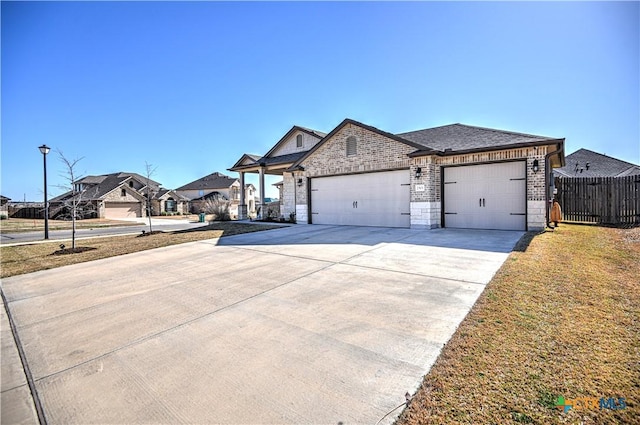 french country inspired facade with stone siding, fence, concrete driveway, a garage, and brick siding