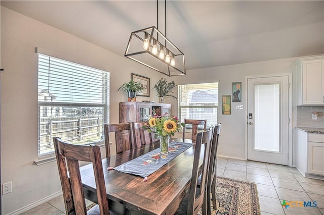 dining area with light tile patterned flooring, a chandelier, and baseboards