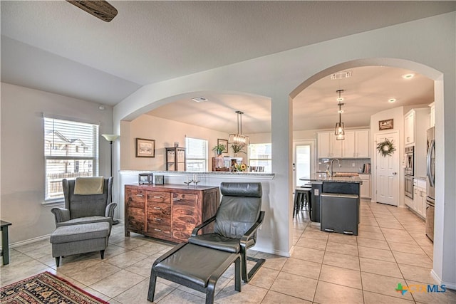 living area with lofted ceiling, light tile patterned floors, arched walkways, and visible vents