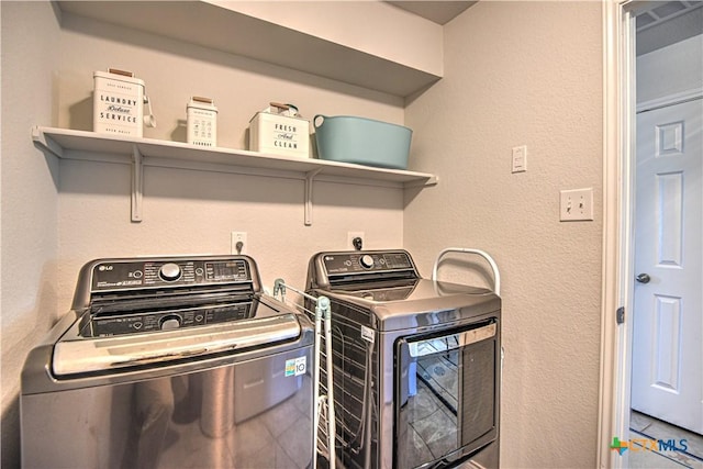 laundry room with washer and clothes dryer, laundry area, and a textured wall