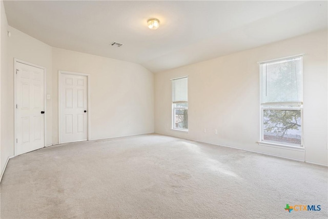 unfurnished room with light carpet, vaulted ceiling, and a wealth of natural light