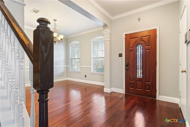 entryway with ornate columns, dark hardwood / wood-style flooring, a notable chandelier, and crown molding