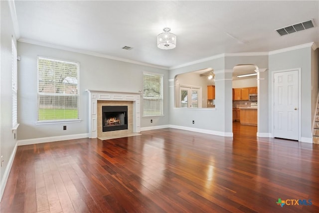 unfurnished living room featuring ornate columns, dark hardwood / wood-style flooring, a fireplace, and ornamental molding