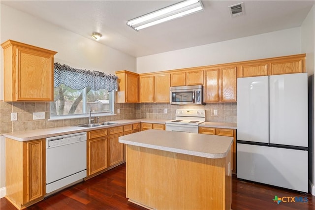 kitchen featuring white appliances, dark wood-type flooring, a kitchen island, sink, and backsplash