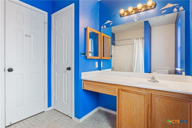 bathroom featuring toilet, tile patterned flooring, walk in shower, and vanity