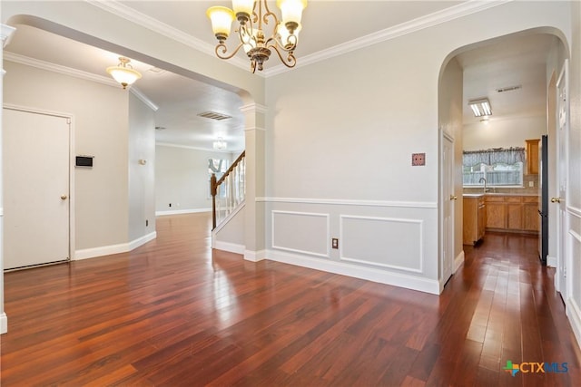 spare room featuring dark hardwood / wood-style flooring, an inviting chandelier, and crown molding