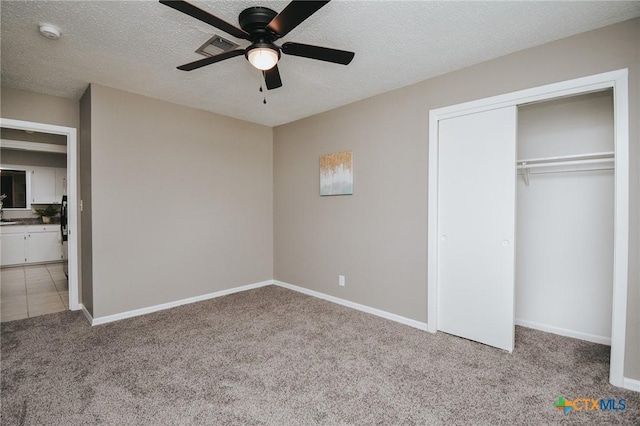 unfurnished bedroom with carpet floors, a textured ceiling, baseboards, visible vents, and a closet