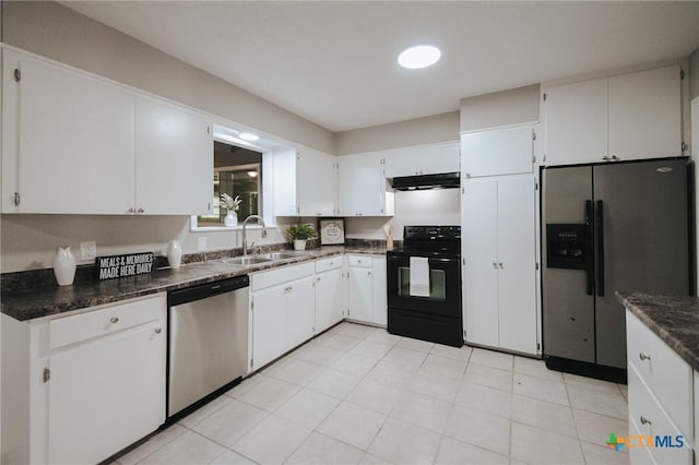 kitchen with dark countertops, appliances with stainless steel finishes, a sink, white cabinetry, and under cabinet range hood