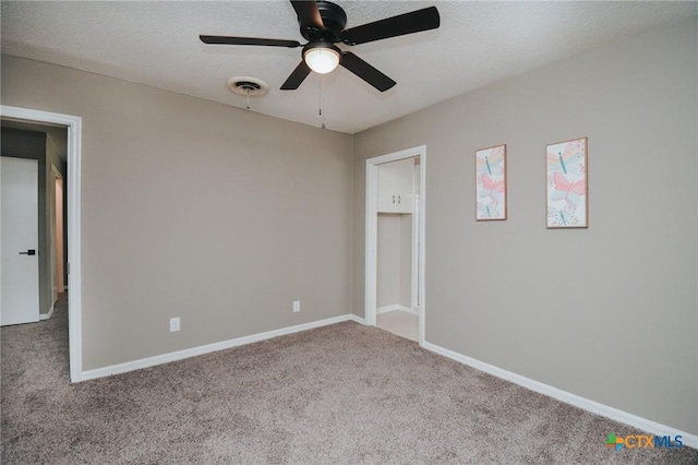 carpeted spare room with baseboards, a textured ceiling, ceiling fan, and visible vents