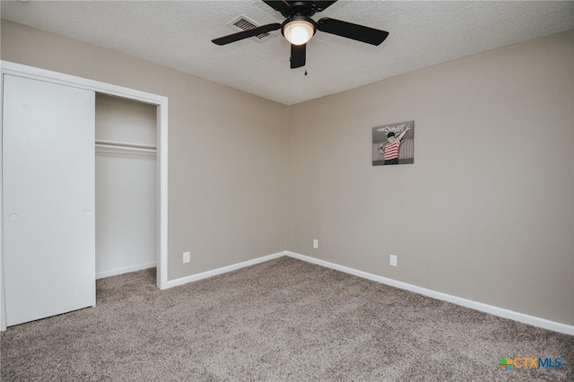 unfurnished bedroom featuring a textured ceiling, visible vents, carpet floors, baseboards, and a closet