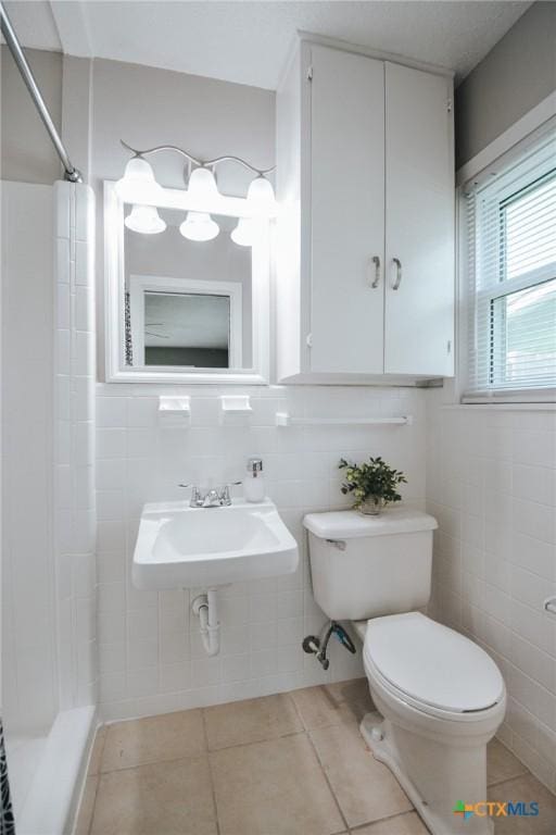 bathroom featuring a sink, tile patterned floors, walk in shower, and toilet