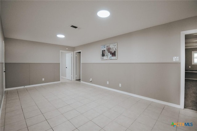 spare room with light tile patterned floors, a wainscoted wall, recessed lighting, and visible vents
