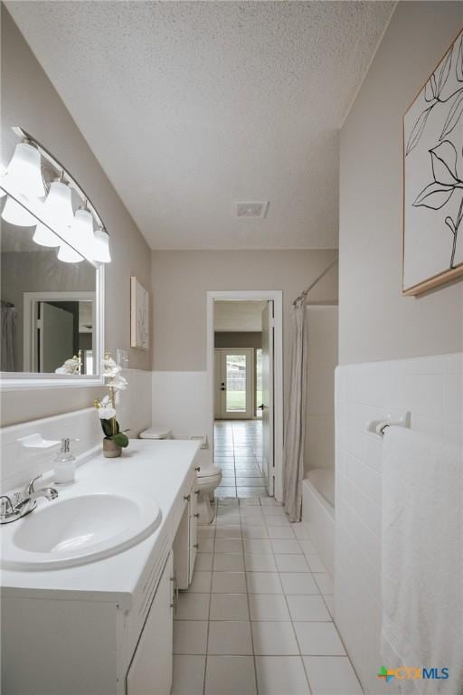 full bath with tile patterned flooring, vanity, a textured ceiling, shower / bathtub combination with curtain, and visible vents