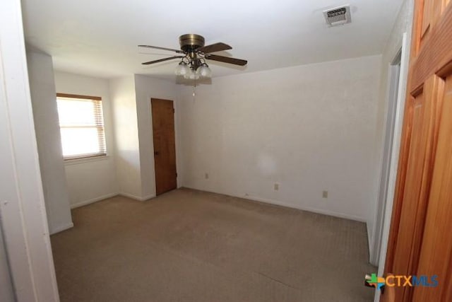 unfurnished room with visible vents, baseboards, light colored carpet, and ceiling fan