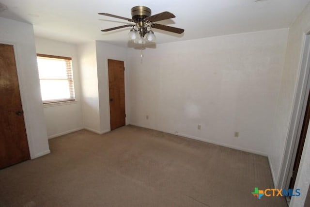 unfurnished bedroom with light colored carpet, baseboards, and a ceiling fan