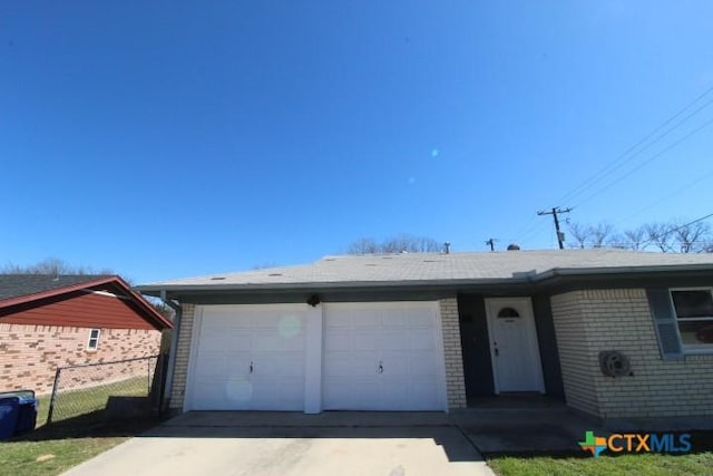 single story home with a garage, brick siding, concrete driveway, and fence